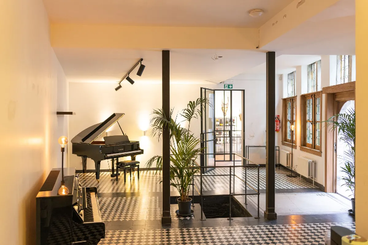 The salon of The Antwerp Pianist with its grand piano and tiled floor